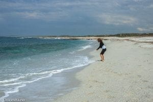 Jente leker i strand av kvarts med blått hav