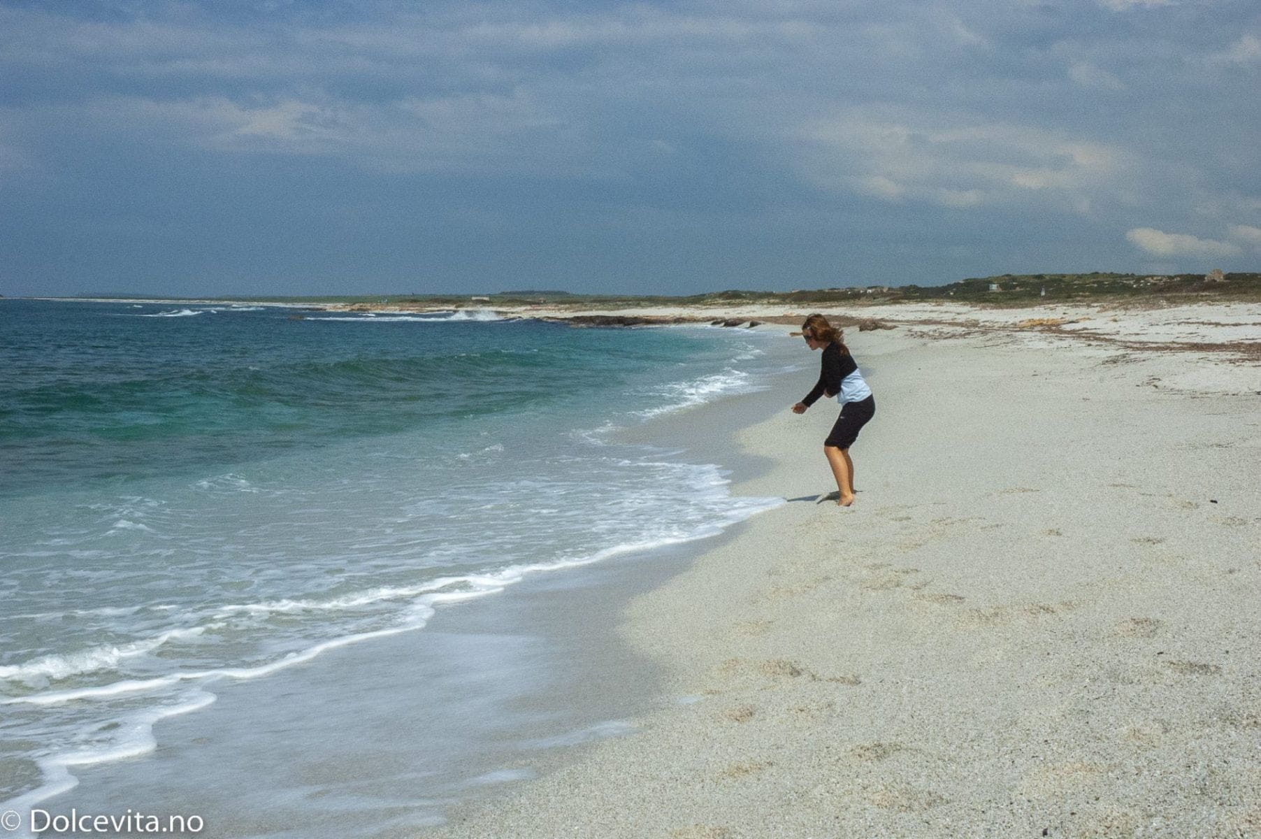 Jente leker i strand av kvarts med blått hav
